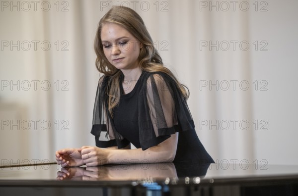 Young woman, pianist, in evening dress leaning on a Steinway & Sons grand piano, Stuttgart, Baden-Württemberg, Germany