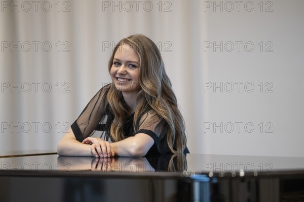 Smiling young woman, pianist, in evening dress leaning on a Steinway & Sons grand piano, Stuttgart, Baden-Württemberg, Germany