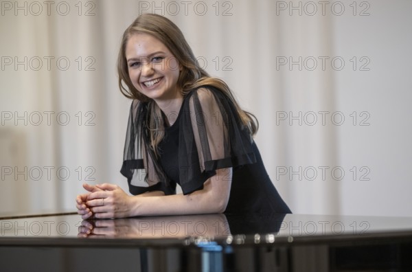 Laughing young woman, pianist, in evening dress leaning on a Steinway & Sons grand piano, Stuttgart, Baden-Württemberg, Germany