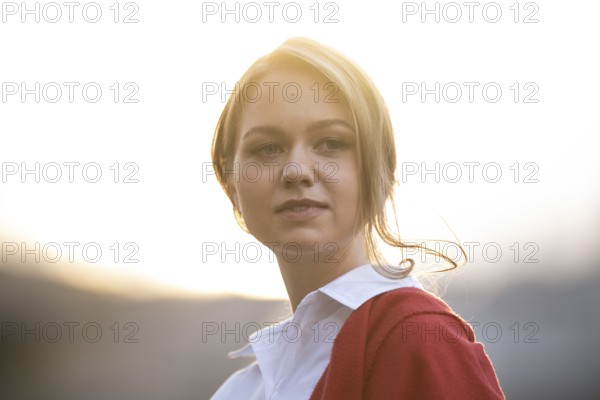 Self-confidently looking young woman in white blouse and red cardigan, in backlight, Stuttgart, Baden-Württemberg, Germany