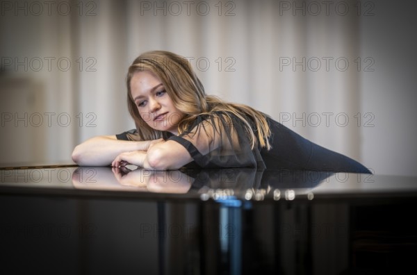 Thought-looking young woman, pianist, in evening dress leaning on a Steinway & Sons grand piano, Stuttgart, Baden-Württemberg, Germany