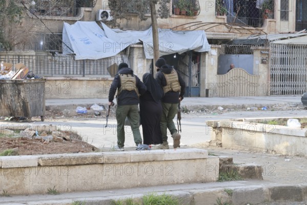 In Aleppo, Syria on January 10, 2026, Syrian Army soldiers assist and secure an elderly woman following fierce battles with the SDF. The deployment comes after Kurdish forces withdrew from the Sheikh Maqsoud and Ashrafieh neighborhoods towards eastern Syria, ending days of heavy military operations in the area, Aleppo, Sheikh Maqsood, Syria