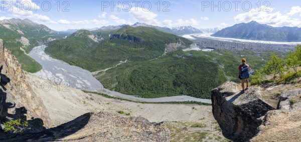 Panorama, young woman on a rocky outcrop enjoying the view, view of impressive mountain landscape with Matanuska glacier and glaciated mountain peaks, Matanuska River River, Lion's Head, Chugach Mountains, Alaska, USA
