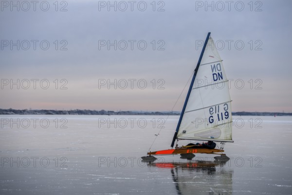 An ice sailboat glides across a frozen lake under a cloudy sky, Dümmer nature park Park, Lower Saxony, Germany
