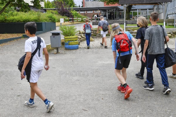 Group of children with school bags, outside on a path in front of school building, Lower Saxony, Germany