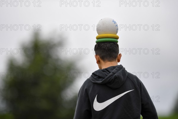 Person with a ball and rings on their head, outside in hoodie, sports and fun Olympics Sportfest Schule, Lower Saxony, Germany