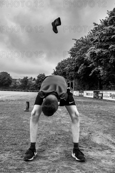 A boy throws a rubber boot on a sports field in a black and white shot, Sports and Fun Olympics Sports Festival School, Lower Saxony, Germany
