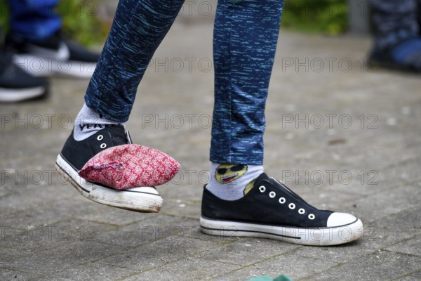 A person with patterned socks and padded shoes stands on a paved floor, Sports and Fun Olympiad Sportfest School, Lower Saxony, Germany