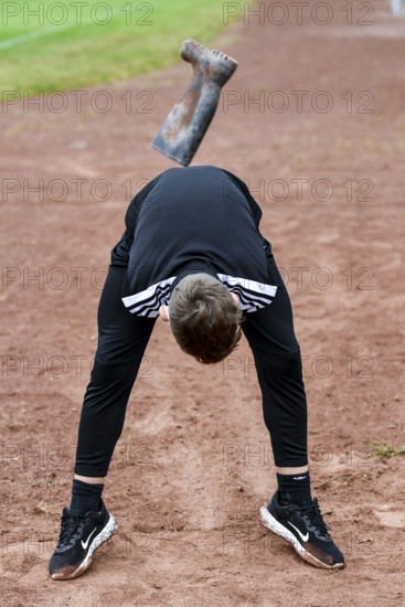 A teenager in sportswear throws a rubber boot on an ash track rubber boots long throw sports and fun Olympics sports festival school, Lower Saxony, Germany