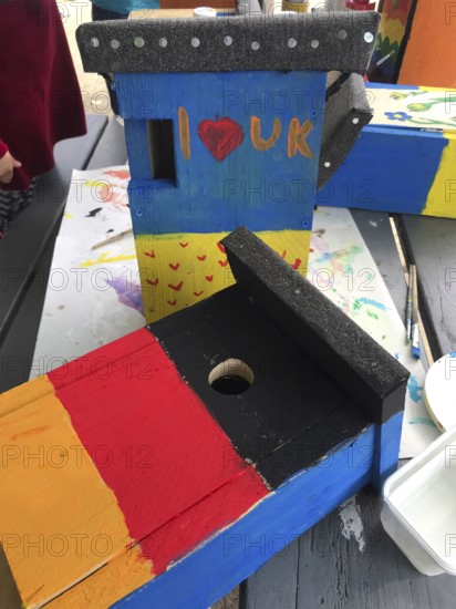 Lower Saxony, Germany, painted bird house in blue and yellow with flowers. Ukrainian students' creative craft project with spring-like design