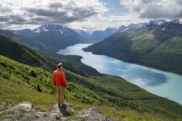 Mountaineer enjoys views of blue lake and mountains on Twin Peaks Trail, Eklutna Lake, Chugach Mountains, Chugach State Park, Alaska, USA