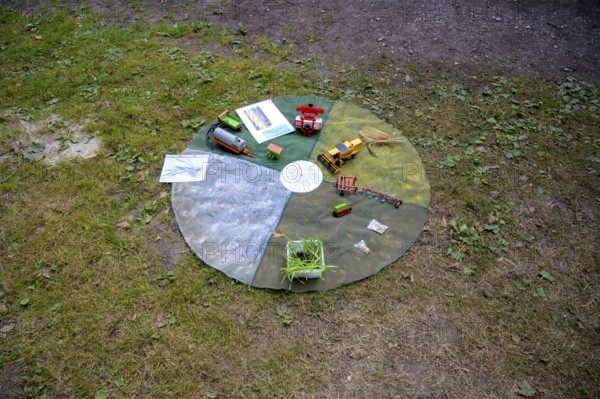 Circular outdoor table with toy vehicles on a grassy area, playful presentation of the individual months in the agricultural year, event for schoolchildren of the campaign Create transparency, Osnabrücker Land, Lower Saxony, Germany