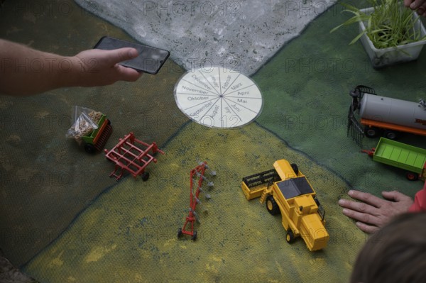 Hand points at a miniature agricultural model with toy vehicles on a table, event for schoolchildren of the Transparency campaign, Osnabrücker Land, Lower Saxony, Germany