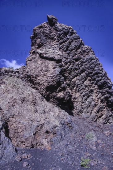 View of a high volcanic rock structure under a clear blue sky, partial view of El Cuervo volcano, Tinajo Lanzarote
