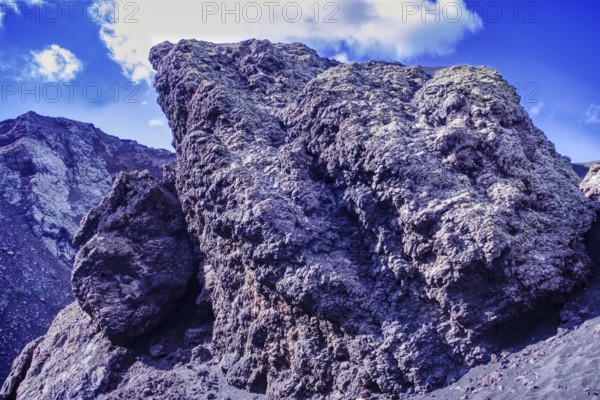 Impressive rock formation of volcanic rock rising against a blue sky, partial view of El Cuervo volcano, Tinajo Lanzarote