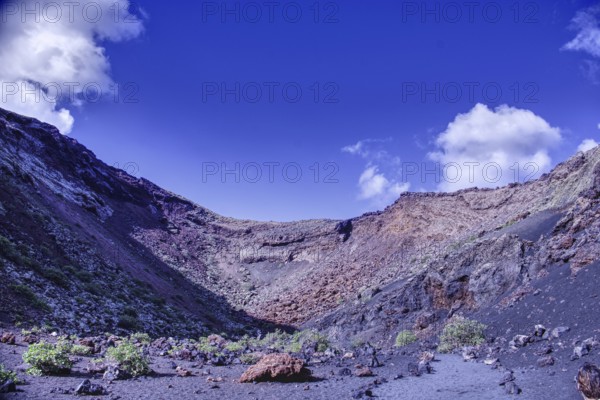 Impressive volcano crater with low vegetation under a blue sky, El Cuervo, Tinajo Lanzarote