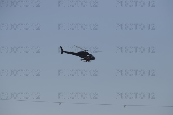 A helicopter over a rope in the sky in twilight conditions, Lemförde, Lower Saxony, Germany