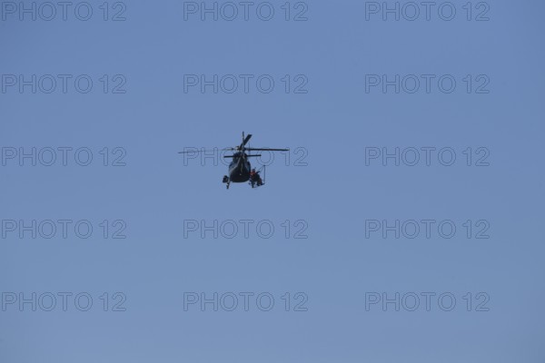 A helicopter can be seen from afar in the blue sky while it is working, Lemförde, Lower Saxony, Germany