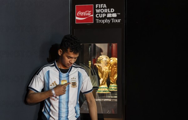 A football fan poses for a photograph with the original FIFA World Cup 2026 Trophy during the official India tour in Guwahati, Assam, India, on January 13, 2026