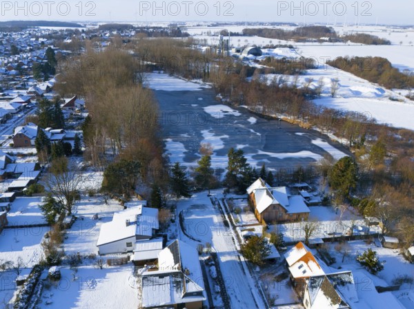 Winter village scene with snow-covered houses and a frozen lake in a quiet landscape, aerial view, Oelsburg, Ilsede, Peine district, Lower Saxony, Germany