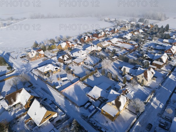 Snowy village with houses and roads next to a large snowy field, aerial view, Oelsburg, Ilsede, Peine district, Lower Saxony, Germany