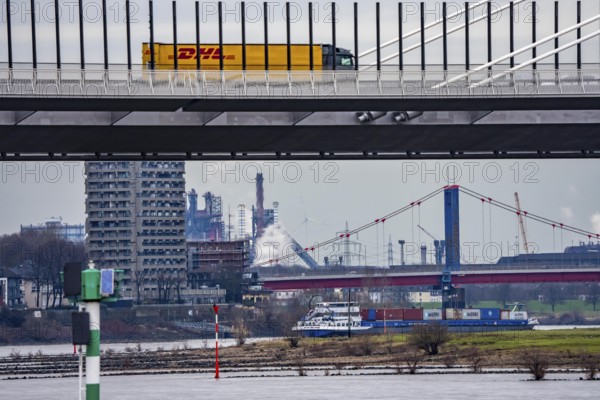 Shipping traffic on the Rhine near Duisburg-Homberg, new A40 motorway, Neuenkamp Rhine bridge, first construction phase, Friedrich-Ebert bridge between Homberg and Ruhrort in the back, industrial setting of the ThyssenKrupp steel plant, DHL trucks, North Rhine-Westphalia, Germany