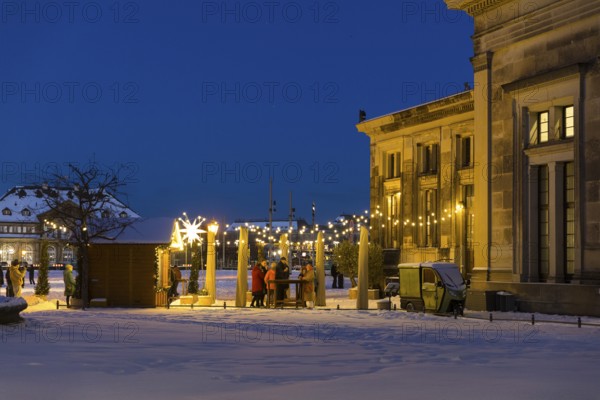 Mulled wine stand behind the Schinkelwache with a view of the Semper Opera House with fairy lights and Herrnhuter Stern in the snow, Christmas atmosphere in the old town of Dresden, Saxony, Germany