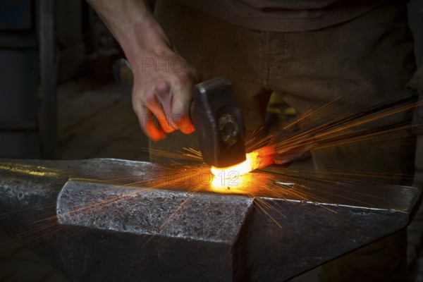 Sparks spray, a blacksmith forging, working at the Ehnert forge in Dresden-Bühlau, Saxony, Germany