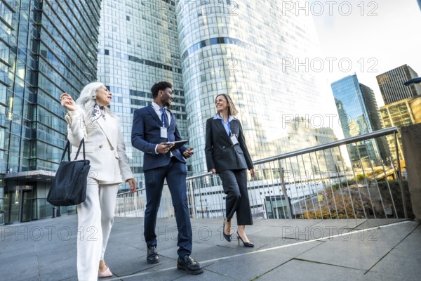 Diverse business professionals walking and discussing in a modern urban city, collaborating and networking while representing corporate success and global teamwork
