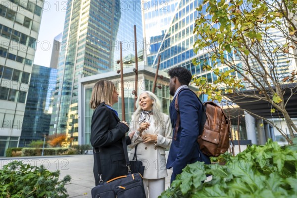 Diverse business professionals conversing and networking outdoors in a vibrant urban environment, surrounded by modern skyscrapers and lush city greenery, representing teamwork and collaboration