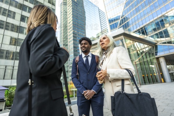Diverse business professionals holding an informal outdoor meeting on a city street, exchanging ideas and collaborating against a backdrop of modern skyscrapers, teamwork and partnership