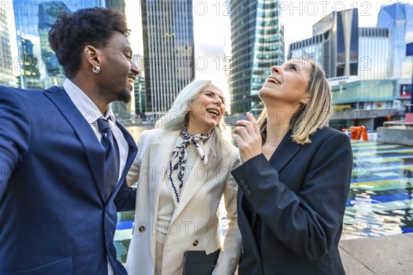 Diverse business team colleagues laughing together while standing outdoors in the city, enjoying a positive moment during a corporate break with urban buildings in the background