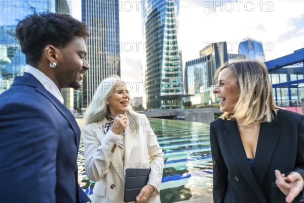Diverse business professionals having a joyful outdoor conversation and networking session in a modern urban environment, fostering teamwork and positive interactions