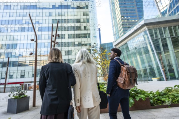 Diverse group of business people walking through a modern urban city district, discussing future plans and collaborating on new projects in a vibrant corporate environment