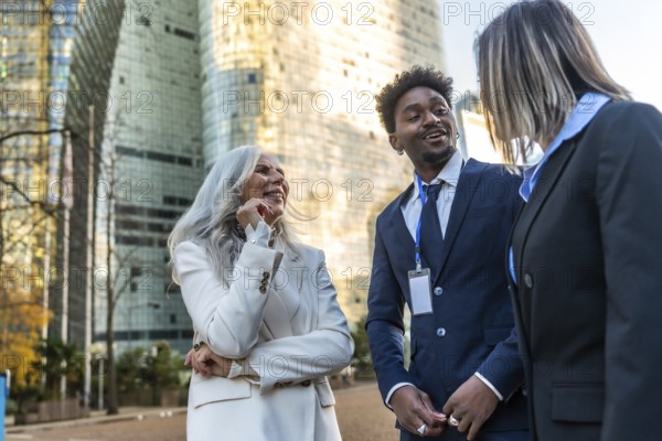 Diverse business professionals sharing a cheerful conversation and networking outdoors in an urban city environment, showcasing collaboration and teamwork