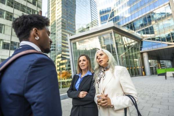 Diverse business professionals having an informal outdoor meeting, discussing ideas and collaborating on a project in a modern urban environment with office buildings