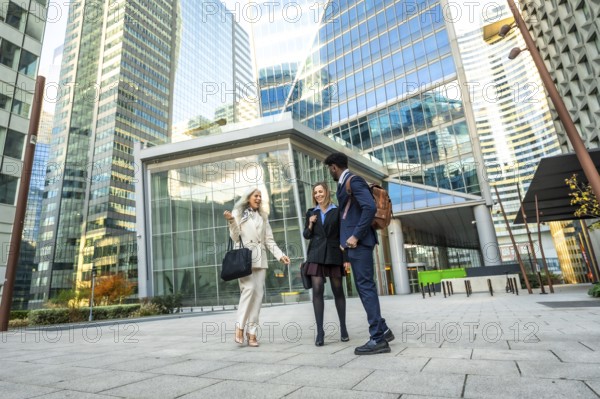 Diverse business professionals having a conversation while walking together through a modern urban financial district, discussing ideas in a dynamic city environment