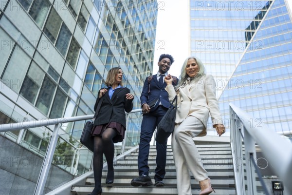 Diverse group of business professionals walking down outdoor stairs in a modern financial district, discussing work and collaborating in a corporate urban environment