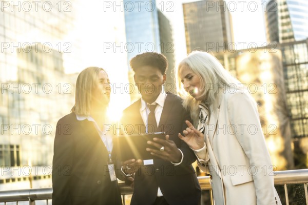 Diverse multi generation business team outdoors at sunset, collaborating over a digital tablet amid urban skyscrapers teamwork, technology and leadership in modern corporate life