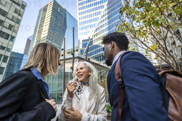 Diverse group of business people collaborating and networking outside in a modern office district, smiling and engaging in conversation about work while building relationships