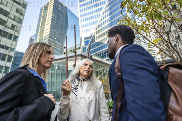 Professionals engaging in a focused conversation outside office buildings, representing collaboration, teamwork, and modern corporate communication in a city environment