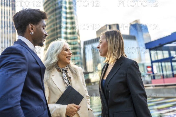 Diverse business people engaging in a professional discussion and teamwork, collaborating outdoors in a modern urban environment with office buildings in the background