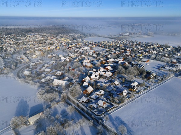 Snowy village under clear sky, sunlight reflected on white roofs and trees, aerial view, partly fog, Bülten, Ilsede, Lower Saxony, Germany