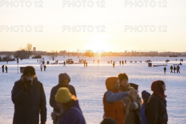 People stand at sunset on Tempelhofer Feld in Berlin on 11.01.2026