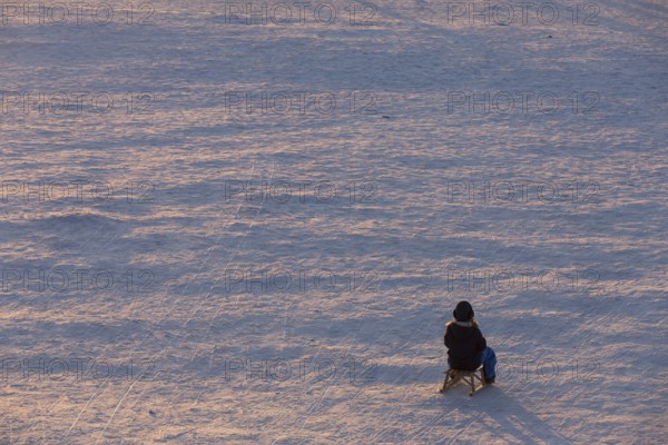 A child sits alone on a sled on Tempelhofer Feld in Berlin on 11.01.2026