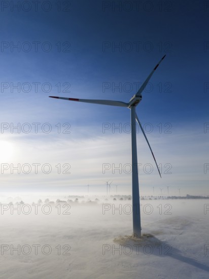 A wind turbine stands out in a snowy, foggy landscape, surrounded by soft morning light and clear sky, aerial view, wind turbine in snow in fog, between Bülten and Solschen, Ilsede, Peine district, Lower Saxony, Germany