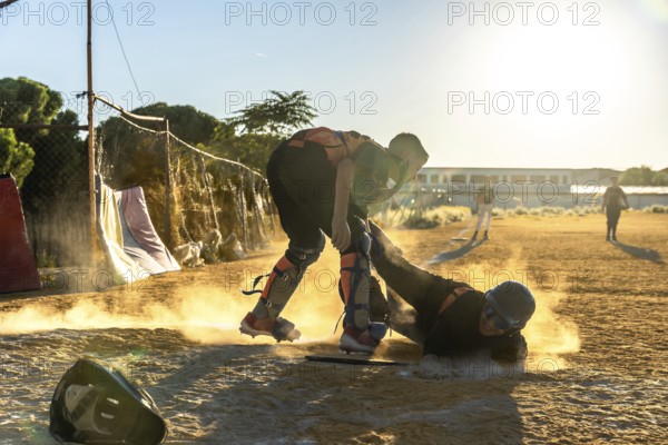 Baseball player slides into home plate at sunset, kicking up dust as catcher crouches ready for a tag during an amateur evening game, full of speed and intensity