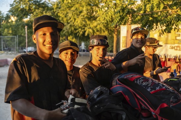 Young baseball players standing together after practice, smiling in jerseys and caps on a sunny outdoor field, showing teamwork, friendship and youthful energy