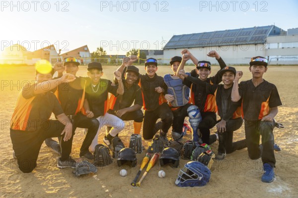 Diverse youth baseball team smiling and cheering on the field at golden hour, surrounded by bats, gloves and helmets after practice or a celebratory win, energetic and united