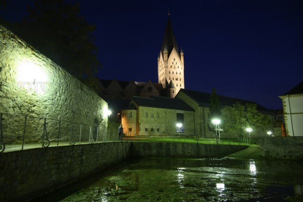 A Gothic church illuminated at night with illuminated tower and dark sky in the foreground the Kaiserpfalz, Paderborn, North Rhine-Westphalia, Germany